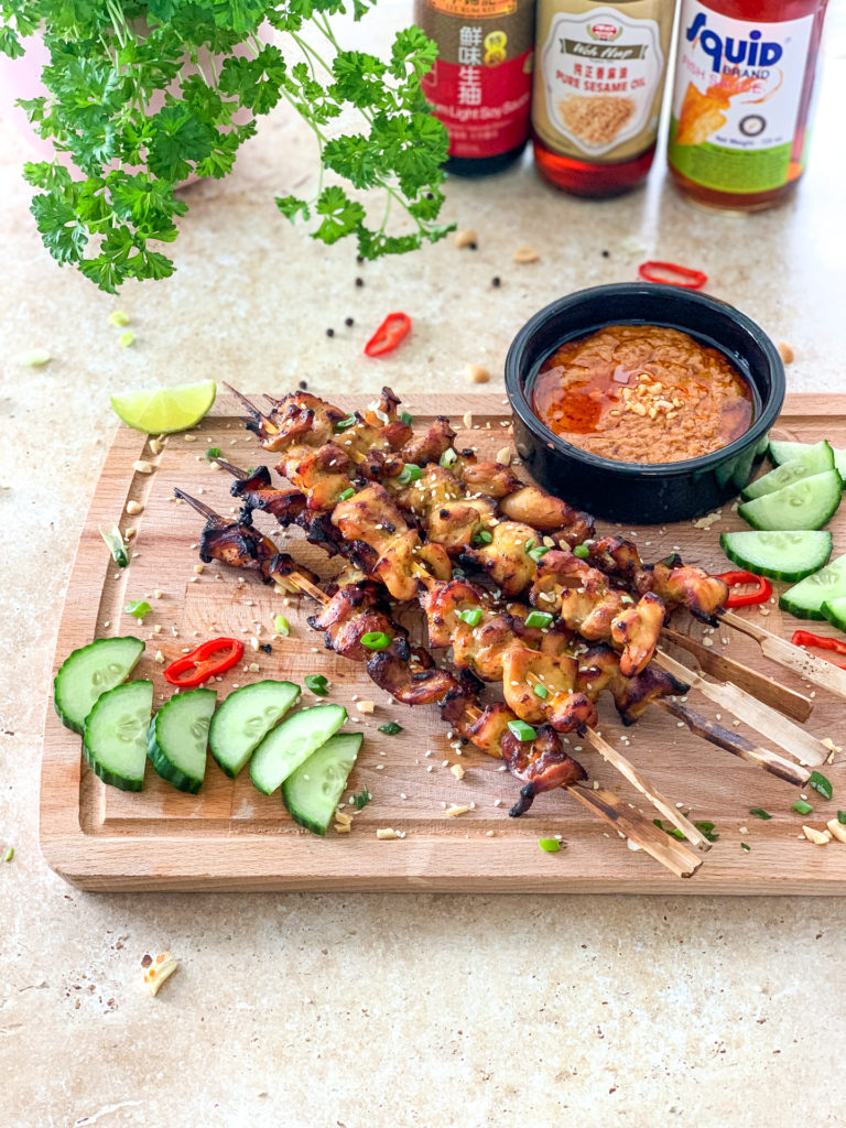 satay chicken skewers with condiments in the background