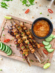 satay chicken skewers on a board with satay sauce