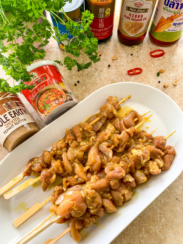 satay chicken on skewers with condiments in the background